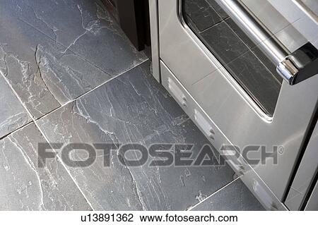 Stock Image - Detail of slate floor and stainless steel oven. Fotosearch