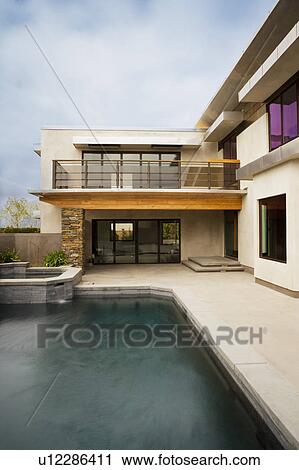 Stock Image - Rear exterior of modern home and swimming pool. Fotosearch
