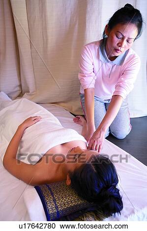 Stock Image - Massage therapist rubbing woman's hand. Fotosearch