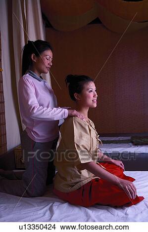 Mature woman massaging young woman's shoulders in therapy room View Large Photo Image Picture - Mature woman massaging young woman's shoulders in therapy room. Fotosearch