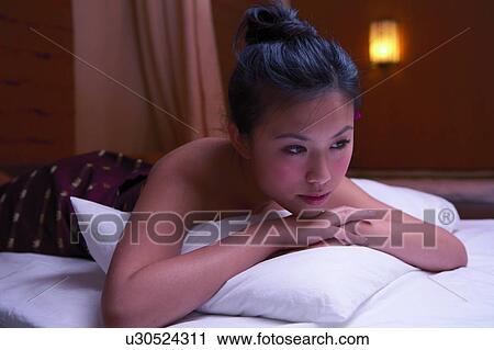 Stock Image - Young womain lying on front in spa room. Fotosearch
