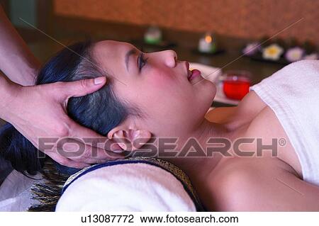 Stock Image - Young woman having head massaged, close-up, side view. Fotosearch