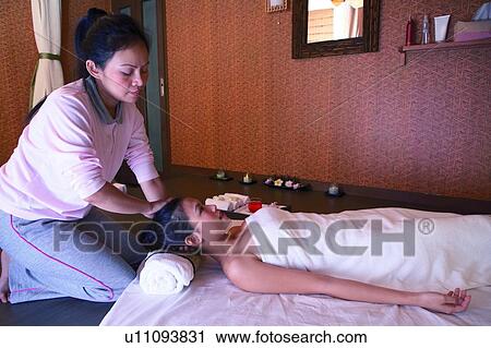 Stock Image - Young woman having neck massaged, side view. Fotosearch