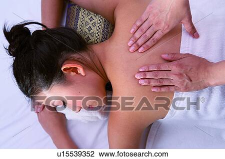 Stock Image - Young woman lying down, receiving back massage, close-up. Fotosearch