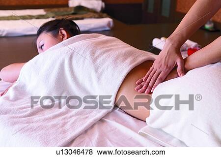 Stock Photo - Young woman massage therapist rubbing woman's back. Fotosearch