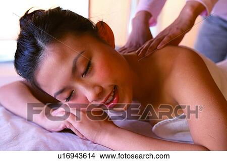 Young woman wearing towel, getting a massage with eyes closed View Large Photo Image Picture - Young woman wearing towel, getting a massage with eyes closed. Fotosearch