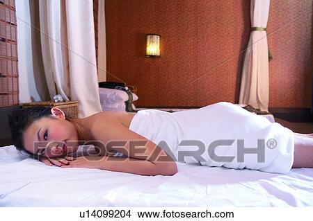 Picture - Young woman wearing towel, lying on front. Fotosearch