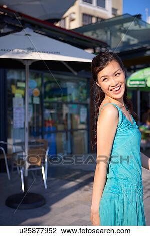 Stock Image - Young Lady Walking in Street, Looking Back. Fotosearch
