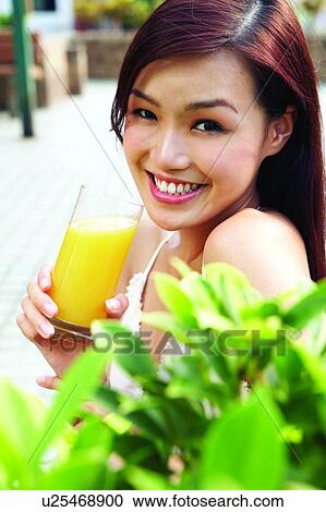 Young woman holding glass of orange juice View Large Photo Image Stock Image - Young woman holding glass of orange juice. Fotosearch