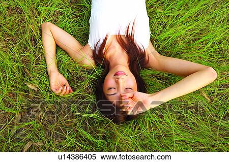 Stock Photography - Young woman lying on grass, eyes closed. Fotosearch