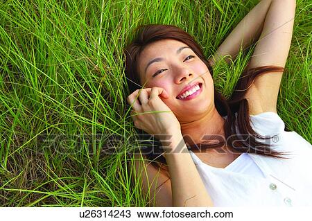 Young woman lying on long grass, smiling cheerfully, close-up View Large Photo Image Stock Image - Young woman lying on long grass, smiling cheerfully, close-up. Fotosearch