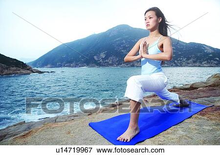 Young woman practising yoga on exercise mat, near the sea View Large Photo Image Stock Photo - Young woman practising yoga on exercise mat, near the sea. Fotosearch