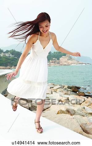 Picture - Young woman running on pavement near the sea. Fotosearch
