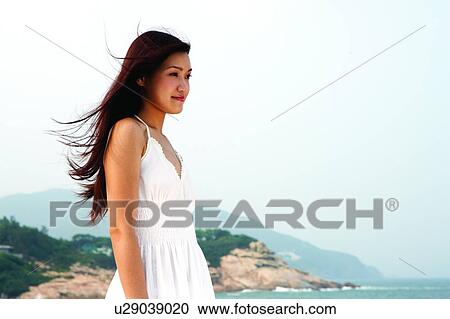 Stock Image - Young woman standing near the sea. Fotosearch