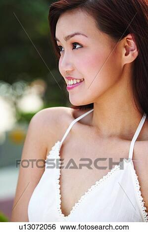 Young woman standing, smiling, side view View Large Photo Image Stock Photograph - Young woman standing, smiling, side view. Fotosearch
