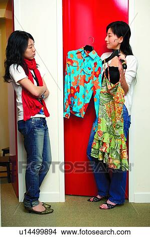 Young woman holding clothes, seeking for advice View Large Photo Image Picture - Young woman holding clothes, seeking for advice. Fotosearch