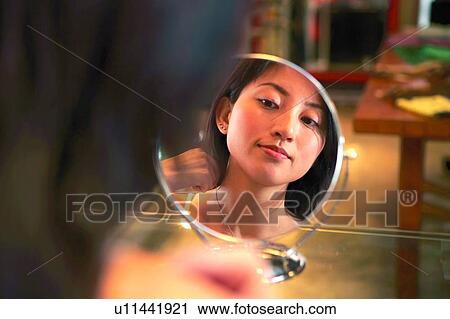 Young woman looking at mirror, trying necklace View Large Photo Image Stock Image - Young woman looking at mirror, trying necklace. Fotosearch