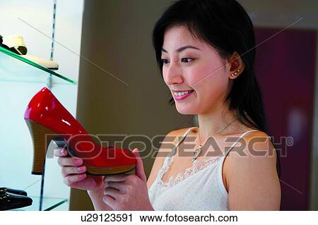 Young woman shopping at boutique, standing, holding a high heel shoe View Large Photo Image Stock Image - Young woman shopping at boutique, standing, holding a high heel shoe. Fotosearch
