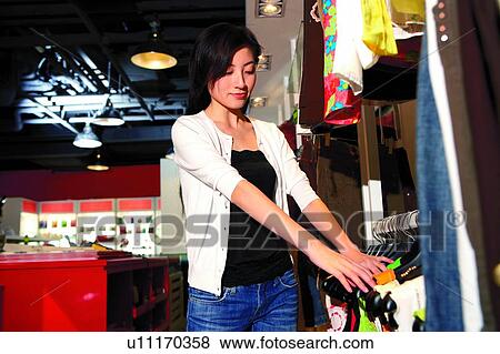 Young woman shopping at boutique, choosing clothes View Large Photo Image Stock Photo - Young woman shopping at boutique, choosing clothes. Fotosearch