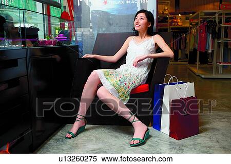 Young woman sitting on sofa, in boutique View Large Photo Image Stock Photography - Young woman sitting on sofa, in boutique. Fotosearch