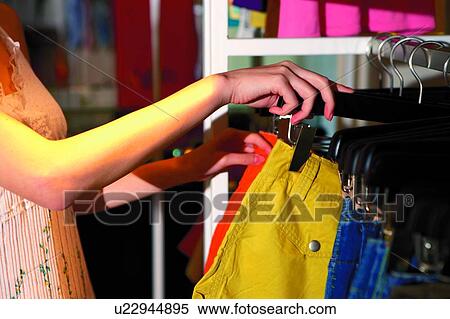 Young woman standing, choosing clothes View Large Photo Image Stock Photography - Young woman standing, choosing clothes. Fotosearch