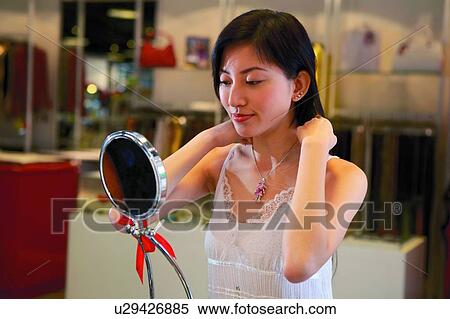 Stock Photography - Young woman trying a cutie necklace. Fotosearch