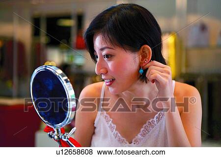 Stock Photo - Young woman trying earings. Fotosearch
