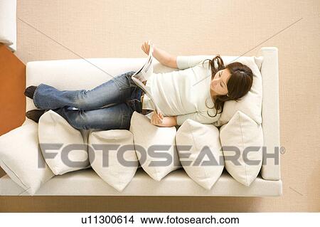 Woman lying on her back with reading View Large Photo Image Picture - Woman lying on her back with reading. Fotosearch