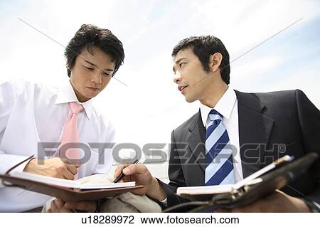 Stock Image - Businessmen having a short meeting. Fotosearch