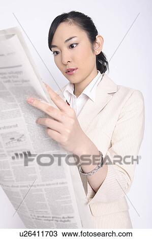 Stock Image - Business lady reading a newspaper. Fotosearch