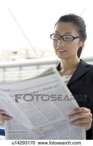 Stock Image - Business lady who reads a newspaper. Fotosearch