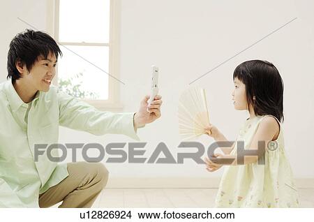 Picture - Father taking a photograph by cell phone. Fotosearch