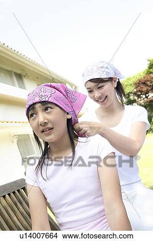 Picture - Mother putting on a bandana to a daughter. Fotosearch