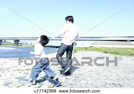 Stock Photo - Parent and child who plays at the shore of the river. Fotosearch