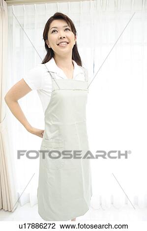 Stock Image - Woman putting on an apron. Fotosearch