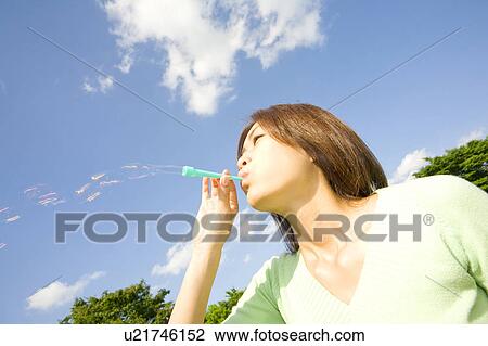 Stock Image - Woman playing soap bubbles. Fotosearch