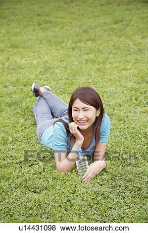 Stock Photo - Woman who is lain at the grass. Fotosearch