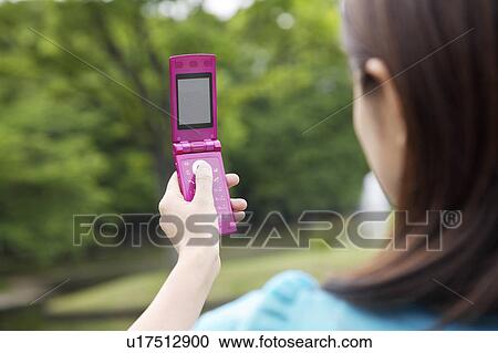 Stock Image - Woman who takes a photograph by cell phone. Fotosearch