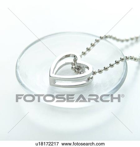 Stock Photo - Heart-shaped pendant on glass plate. Fotosearch