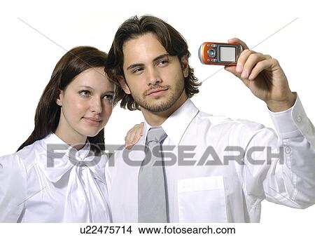 Close-up of a businessman and a businesswoman taking a picture of themselves with a mobile phone View Large Photo Image Picture - Close-up of a businessman and a businesswoman taking a picture of themselves with a mobile phone. Fotosearch