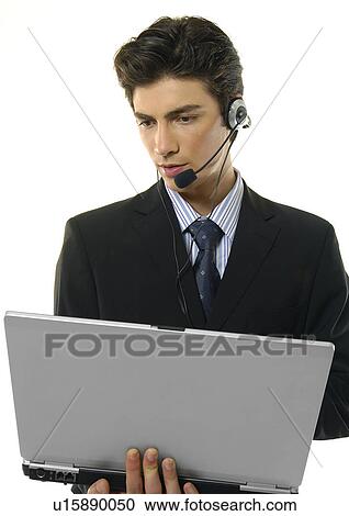 Stock Image - Close-up of a businessman wearing a headset and using a laptop. Fotosearch
