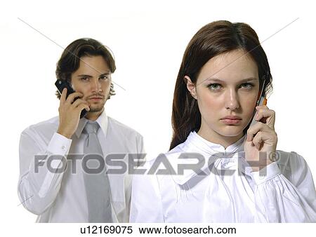 Stock Photography - Portrait of a businessman and a businesswoman using mobile phones. Fotosearch