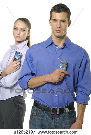 Stock Photo - Portrait of a young couple holding their mobile phones. Fotosearch