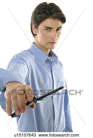 Stock Image - Portrait of a young man offering a mobile phone. Fotosearch
