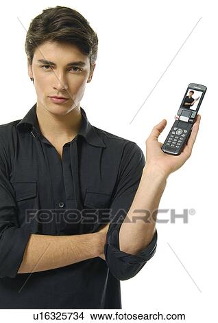 Picture - Portrait of a young man showing a mobile phone. Fotosearch