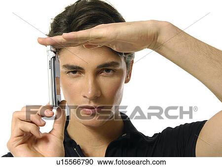 Stock Image - Portrait of a young man showing a mobile phone. Fotosearch