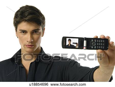 Stock Photograph - Portrait of a young man showing a mobile phone. Fotosearch