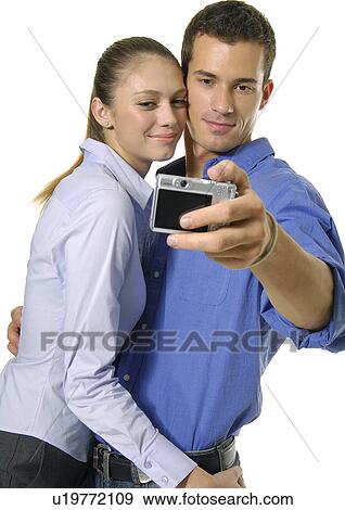 Stock Photo - Side profile of a young couple taking a picture with a mobile phone. Fotosearch