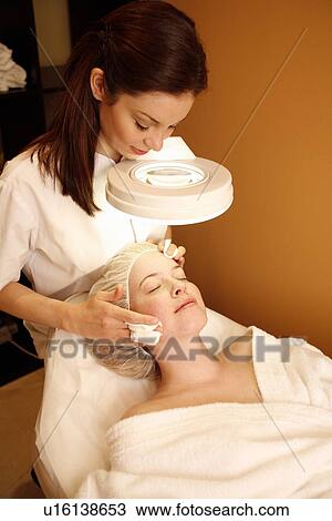 Stock Image - Woman having a facial treatment at a spa. Fotosearch