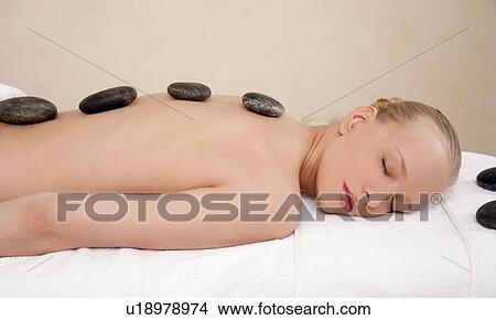 Picture - Young woman enjoying a hot stone massage. Fotosearch